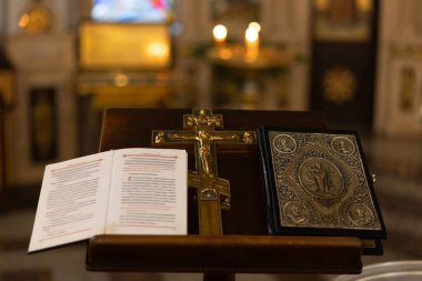 Geleneksel ayin sırasında Ortodoks kilisesinin iç kısımlarında altın haçın açık dua kitabı ve süslü İncil ile yakın plan görüntüsü. Ruhanilik, inanç ve Hristiyanlık kavramları.