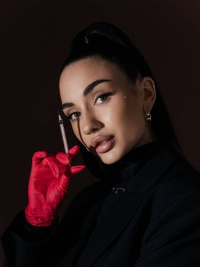 Kendine güvenen genç bayan kozmetik uzmanı elinde şırınga tutan kırmızı eldiven. Estetik tıp güzellik prosedürü Yaşlanma karşıtı tedavi kavramı.