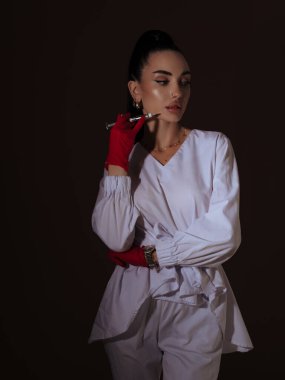 Zarif genç bayan doktor ya da hemşire kozmetik uzmanı elinde enjektör kalem tutan beyaz üniformalı kırmızı eldivenler. Estetik tıp kendi kendini yönetme prosedür kavramı.