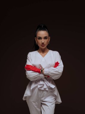 Kendine güvenen genç bayan doktor ya da hemşire kozmetolog beyaz üniformalı kırmızı eldivenli eller çapraz. Profesyonel estetik tıp otoritesi ve uzmanlık konsepti.
