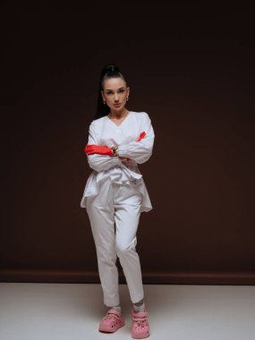 Kendine güvenen genç bayan doktor ya da hemşire kozmetolog beyaz üniformalı kırmızı eldivenler. Profesyonel estetik tıp otoritesi ve uzmanlık konsepti.