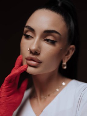 Yakın plan portre genç bayan doktor ya da hemşire kozmetolog beyaz üniformalı kırmızı eldiven yüzünü çeviriyor. Profesyonel estetik tıp, sağlık hizmeti kavramı.