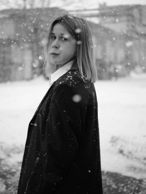 Kar yağarken kameraya bakan şarap lekesi olan tek renkli kadın portresi. Kış kentsel ortamında güçlendirme ve çeşitlilik kavramı.