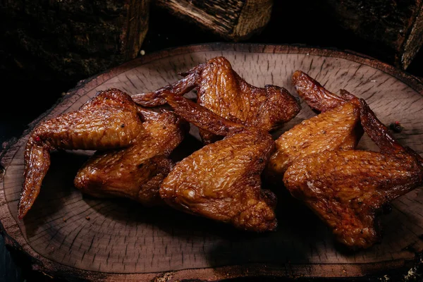 Smoked chicken wings on a dark wooden background close up.