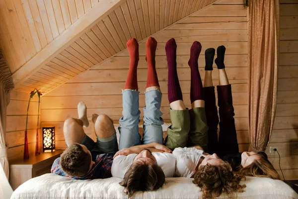Company of young friends in colored socks upside down on wooden wall background. High quality photo