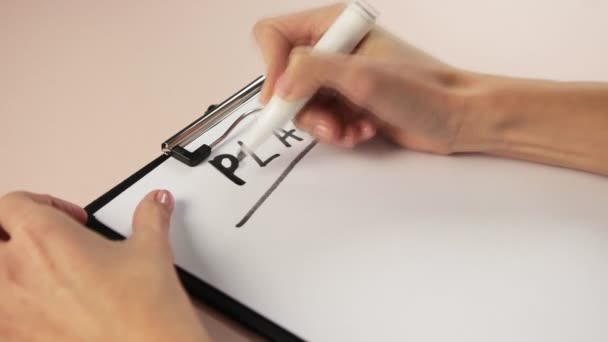 Sluiten van meisje hand schrijven op notitieblok. Schrijf een plan met een markering op wit papier. — Stockvideo
