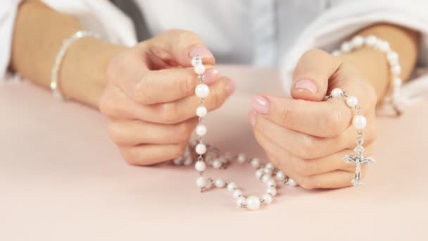 Una giovane ragazza con belle mani tiene un rosario e prega. Colori piacevoli e delicati. — Video Stock