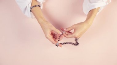 Güzel elleri olan genç bir kız tespih çeker ve dua eder. Hoş ve narin renkler.