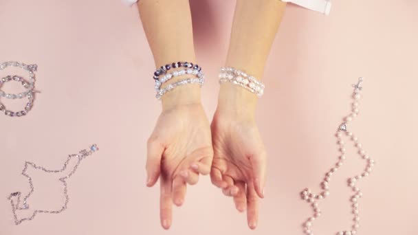 Flickan provar smycken på handen, armband som hon gör själv, utsikten uppifrån. Vacker komposition. — Stockvideo