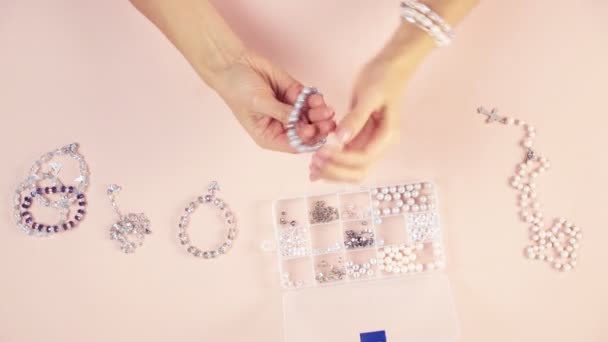 Het meisje probeert sieraden aan de hand, armbanden die ze zelf maakt, het uitzicht van boven. Prachtige samenstelling. — Stockvideo