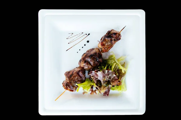 Pig kebab on a stick on a plate with green salad — Stock Photo, Image