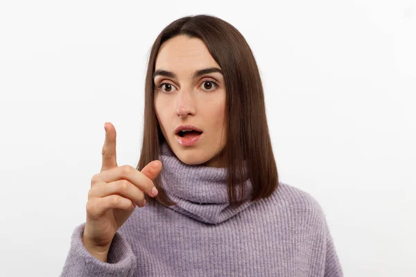 Calma jovencita señala su dedo hacia un lado sobre un fondo blanco. Mira hacia otro lado. —  Fotos de Stock