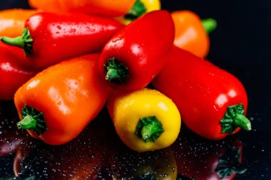 Taze dolmalık biberler renkli bir arka plan yaratıyor, telif hakkı için bir yer. Su sıçramalı siyah arkaplan.