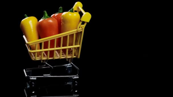Concepto de compra. mini pimientos anaranjados y amarillos en una cesta girando sobre un fondo oscuro. — Vídeos de Stock