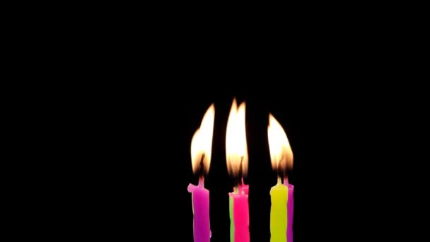 Барвистий вогонь свічки на святкуванні дня народження, дме на чорному фоні ізольовано . — стокове відео