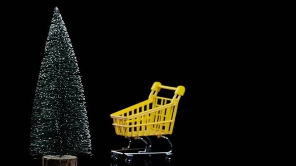 Carro de la compra de comestibles vacío con luces de Navidad y árbol de Navidad, fondo negro. lugar para el texto, descuentos de viernes negro y ventas, feliz año nuevo — Vídeo de stock