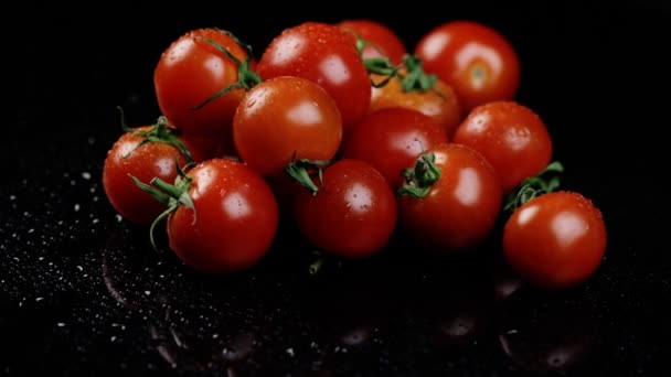 Tomates cereja frescos em um fundo preto com gotas de água close-up. Rotação — Vídeo de Stock