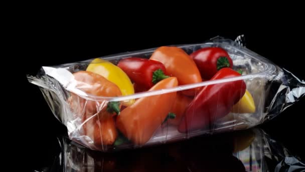 Fresh juicy bell peppers in a transparent pack packed rotating on a black background — Stock Video