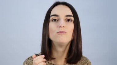 Parlak makyajlı genç bir kız iştah açıcı kremalı pasta yer, gülümser. Yakın plan.