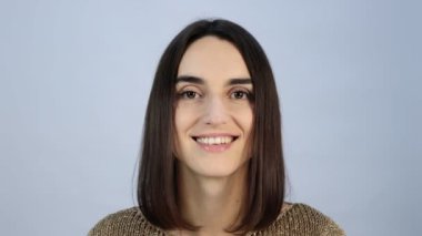 Saç kesimi meydanındaki esmer kız kameraya bakıyor ve elleriyle saçlarını düzleştiriyor.