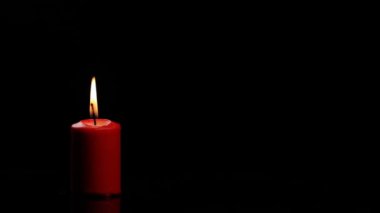 Kırmızı mum yanar ve söner ve siyah arka planda güzel bir duman verir.