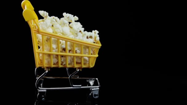 Cestino giallo pieno di vortici di popcorn su uno spazio di sfondo nero per il testo — Video Stock