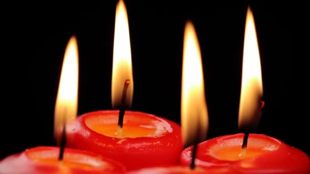 Quatro velas vermelhas estão queimando lentamente girando em um fundo preto — Vídeo de Stock