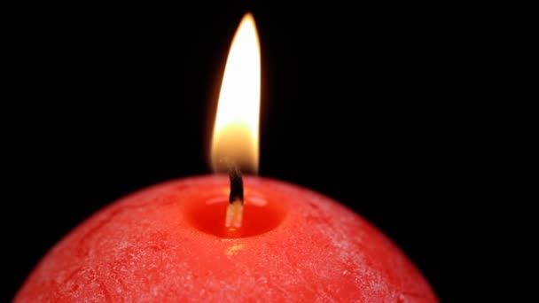 Burning red candle close up swirls on a black background — Stock Video