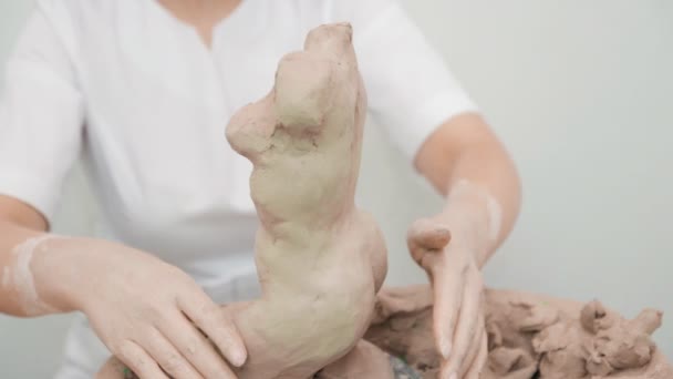 Close up view of women hands working on human torso from pottery clay. — Stock Video