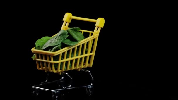 Gevuld met verse plakjes mini spinazie om te winkelen draaiend op een zwarte achtergrond. Het concept van winkelen en gezond eten. — Stockvideo