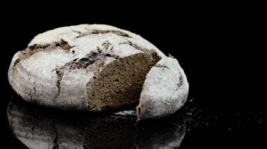 Siyah arka planda un serpiştirilmiş taze siyah ekmek..