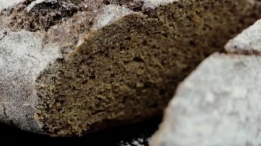 Koyu bir zemine un serpiştirilmiş taze gri ekmek. Kapat..
