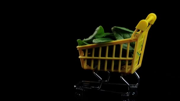 Lleno de rebanadas frescas de mini espinacas para ir de compras girando sobre un fondo negro. El concepto de compras y alimentación saludable. — Vídeo de stock