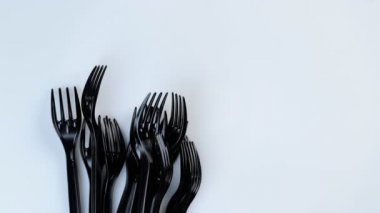 Birçok siyah plastik tek kullanımlık çatal beyaz arka planda döner.