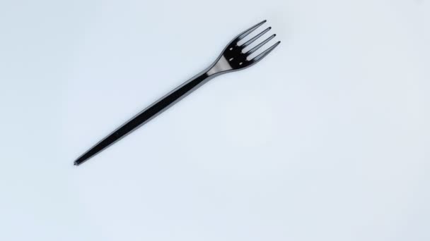 Svart plast engångs gaffel roterar i en cirkel på en vit bakgrund. — Stockvideo