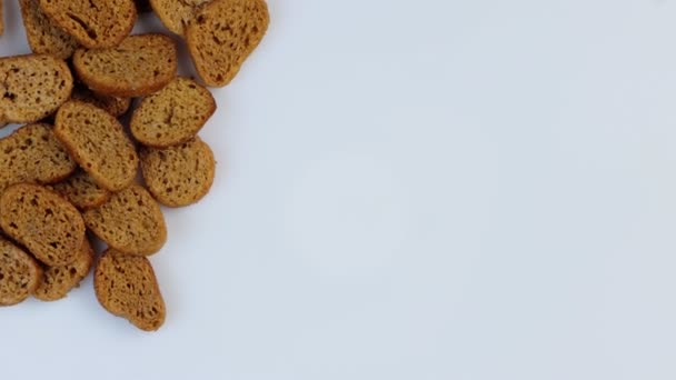 Fette biscottate di pane di grano scuro che filano in cerchio su uno sfondo bianco. Il concetto di cibo sano senza glutine — Video Stock