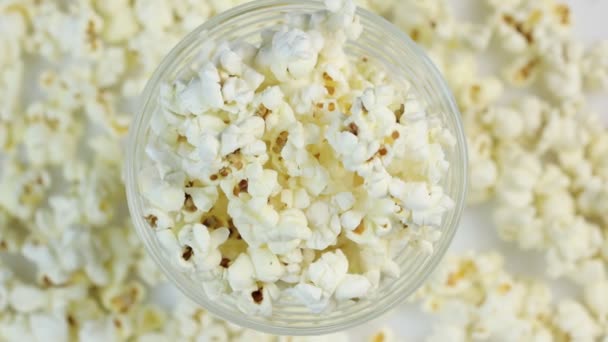 Popcorn v talíři uprostřed rámu, otáčí se na popcornovém pozadí. Místo pro text. — Stock video