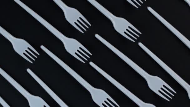 Eco concept. Plastic disposable forks stacked in rows on a black background rotate in a circle. Pattern — Stock Video