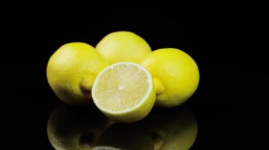 Çemberde dönen taze limonlar, siyah arkaplan ve metin için boşluk. Yansımalar ve su flapları.