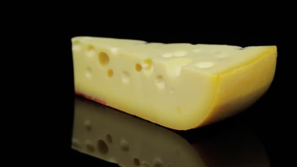 Morceau de fromage à pâte dure tournant en cercle, fond noir et espace pour le texte. — Video