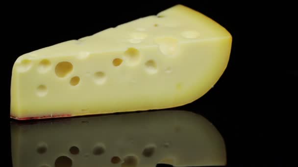 Шматок твердого сиру, що обертається в колі, чорний фон і простір для тексту . — стокове відео