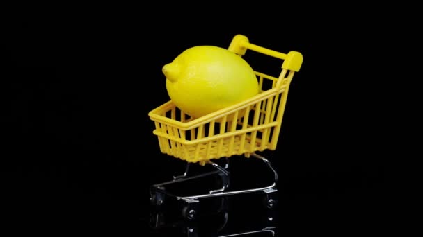 Siyah arka planda sarı bir alışveriş sepetinde limon. Döndürme. — Stok video