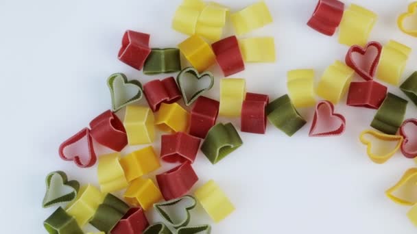 Pasta colorata sotto forma di cuori che girano su uno sfondo bianco. Rotazione. Spazio per testo. — Video Stock