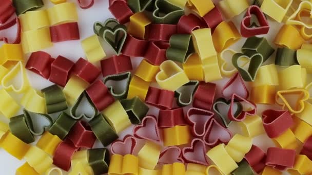 Pasta colorata sotto forma di cuori che girano su uno sfondo bianco. Rotazione. — Video Stock