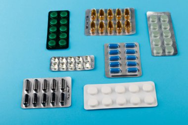 İlaç ve ilaç hapları mavi masadaki paketlerde.