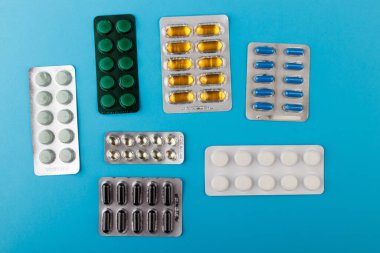 İlaç ve ilaç hapları mavi masadaki paketlerde.