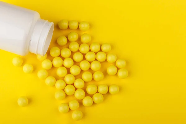 Cápsulas de vitamina. Pílulas de vitamina C e frasco de pílula no fundo amarelo. Vista superior. — Fotografia de Stock