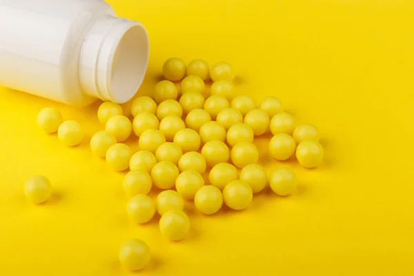 Gula C-vitaminkapslar spilldes ut ur en vit burk mot en gul bakgrund. Ta hand om din hälsa. Vitaminer och mineraler. Fri yta — Stockfoto
