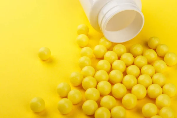 Cápsulas amarelas de vitamina C derramadas de um frasco branco contra um fundo amarelo. Cuida da tua saúde. Vitaminas e minerais. Espaço livre — Fotografia de Stock