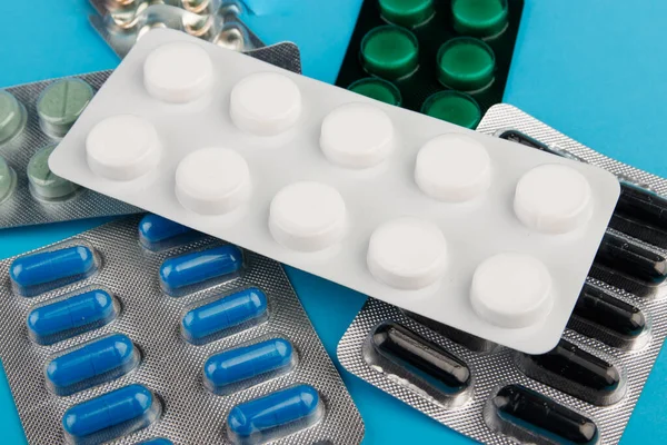 Tumpukan pil dalam blister kemasan di meja biru. Konsep kesehatan, pecandu narkoba atau senjata kimia. Close-up. Stok Gambar